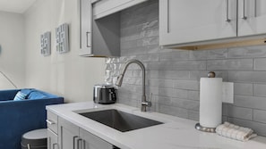 A modern kitchen with a stainless steel sink, a toaster, and a towel dispenser.