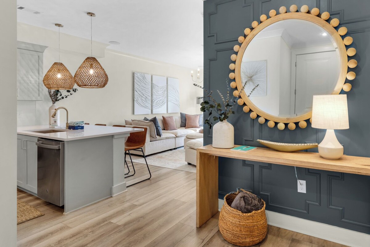 A modern kitchen with a central island, pendant lights, and a large mirror with a wooden frame.