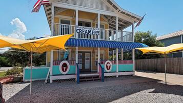 A creamery with a porch, American flags, and yellow umbrellas.
