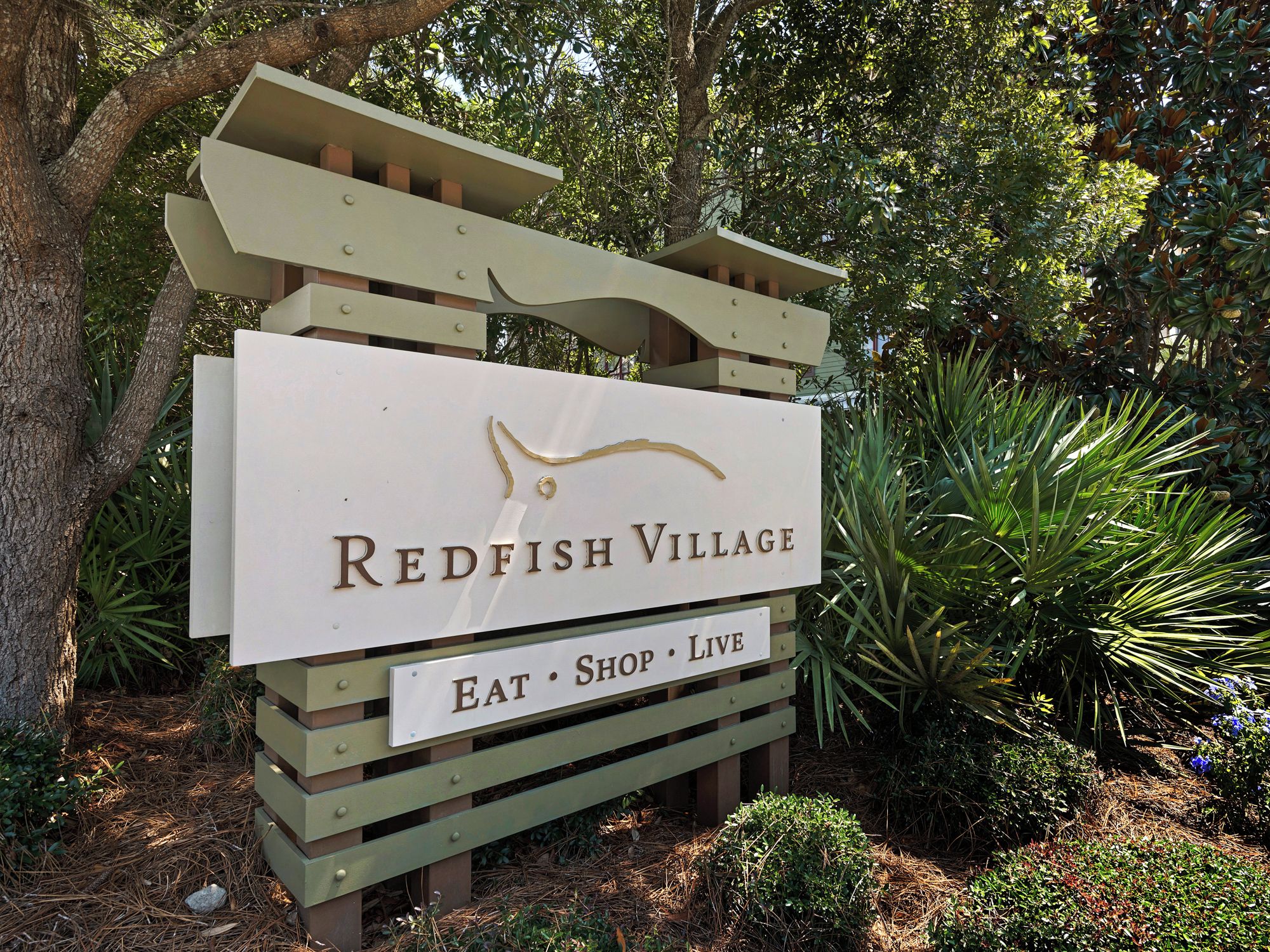 A sign for Redfish Village with a logo and the words "EAT • SHOP • LIVE" below it.