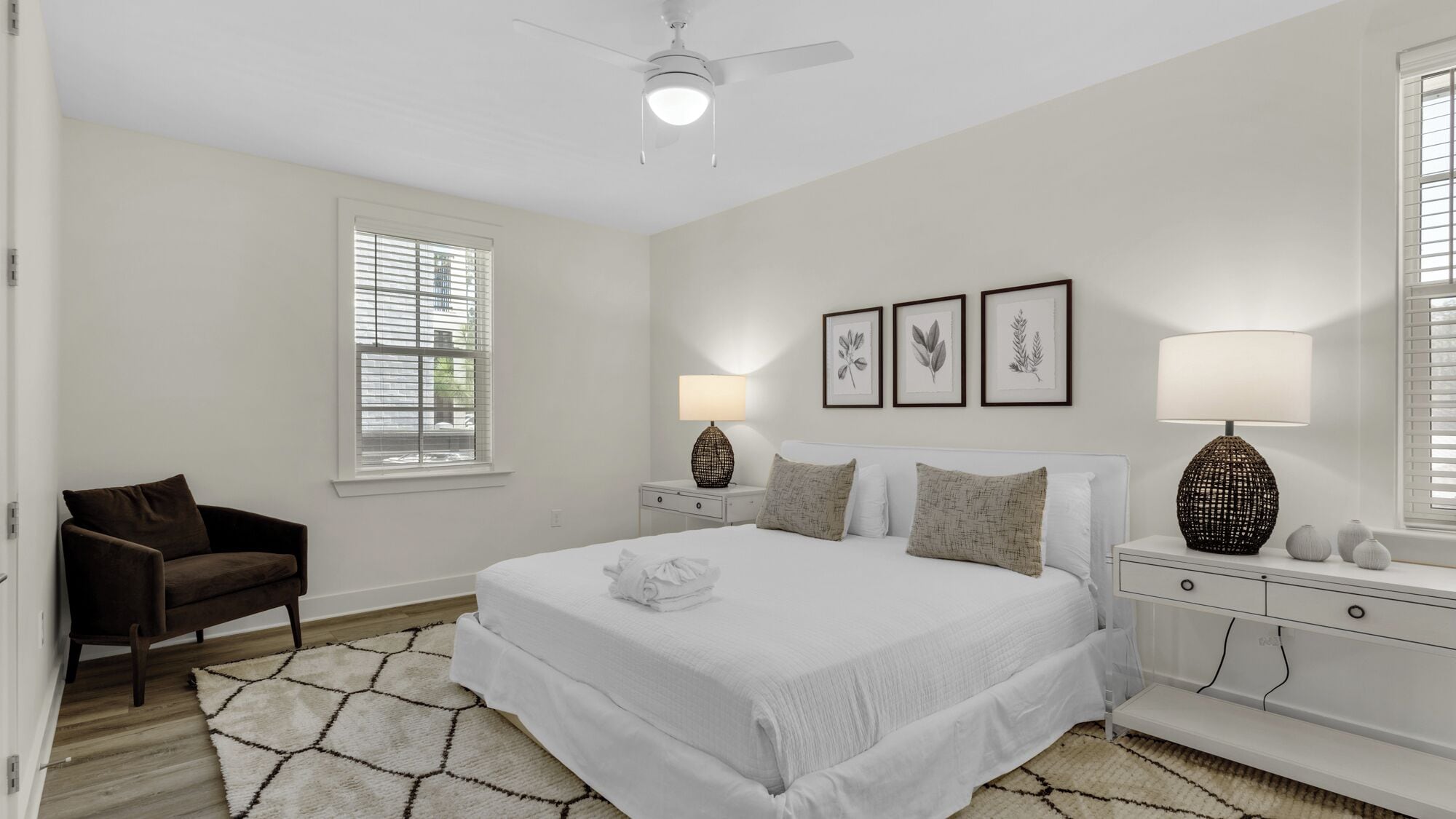 A bedroom with a bed, two bedside tables, a chair, and a ceiling fan.
