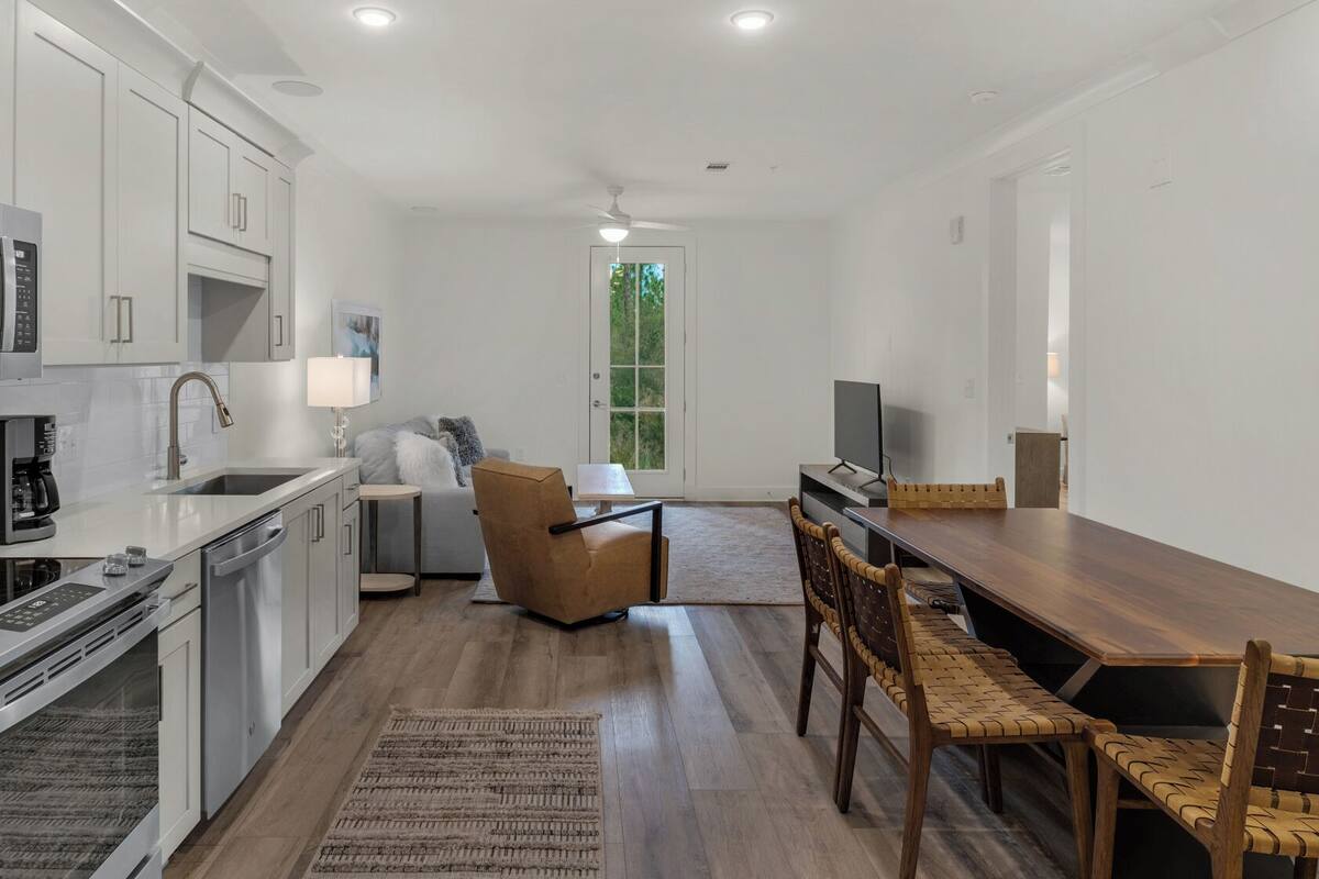 A modern kitchen with white cabinetry, a stainless steel range, and a coffee machine.