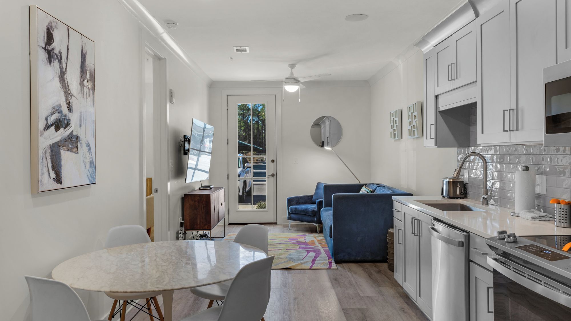 A modern kitchen with white cabinets, a built-in oven, and a stainless steel sink.