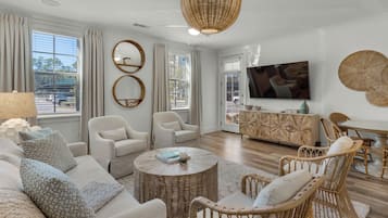 A modern living room with a sofa, two armchairs, a coffee table, and a TV.