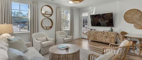 Una sala de estar moderna con un sofá, dos sillones, una mesa de centro y un televisor.