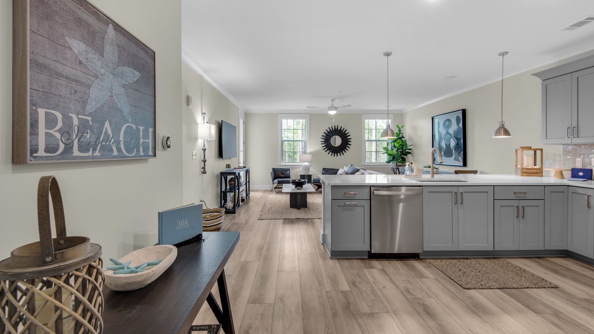 A modern kitchen with grey cabinets, a central island, and a dining area with a bench.