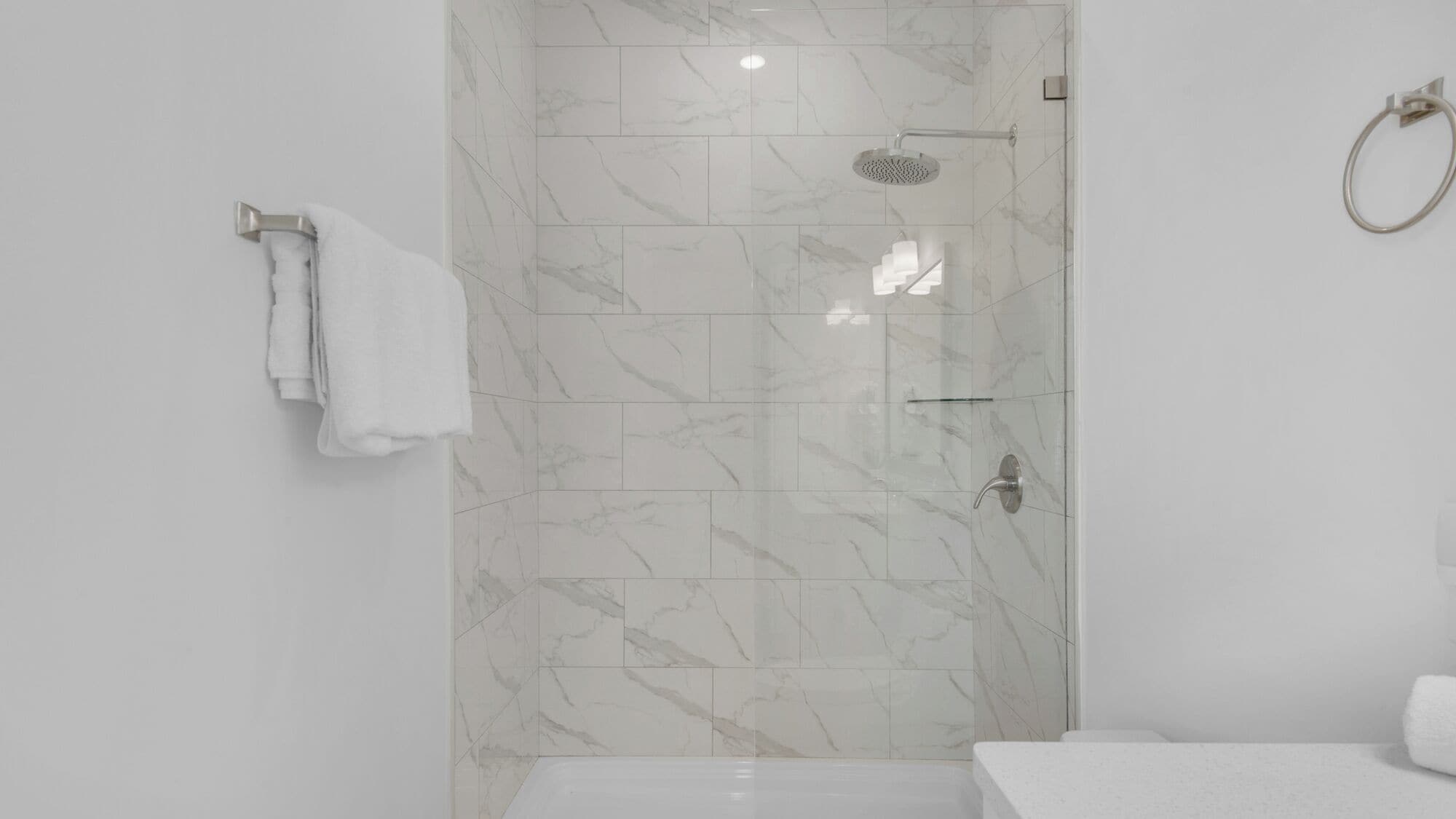 A modern bathroom with a shower, a toilet, and a sink.