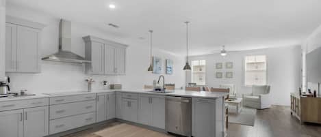 A modern kitchen with grey cabinets, a dishwasher, and pendant lights.