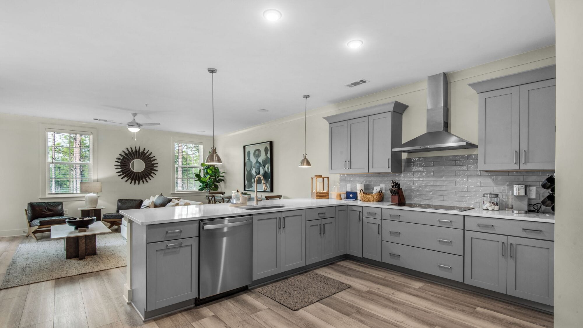 A modern kitchen with grey cabinets, a large island, and a dining area with a sofa and coffee table.