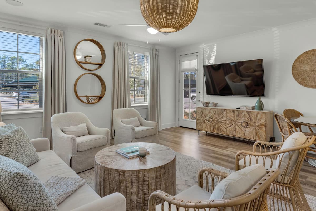 A modern living room with a sofa, two armchairs, a coffee table, and a TV.