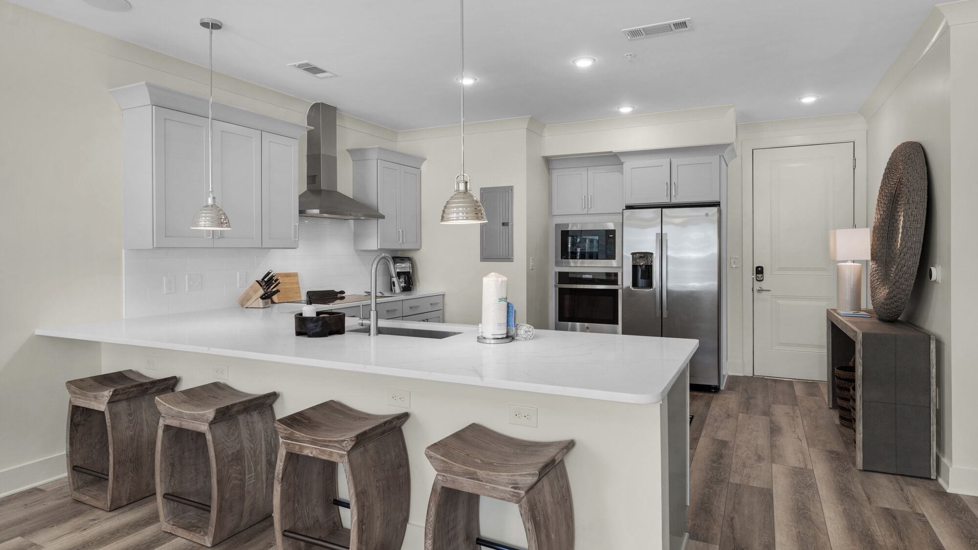 A modern kitchen with a large island, stainless steel appliances, and wooden bar stools.