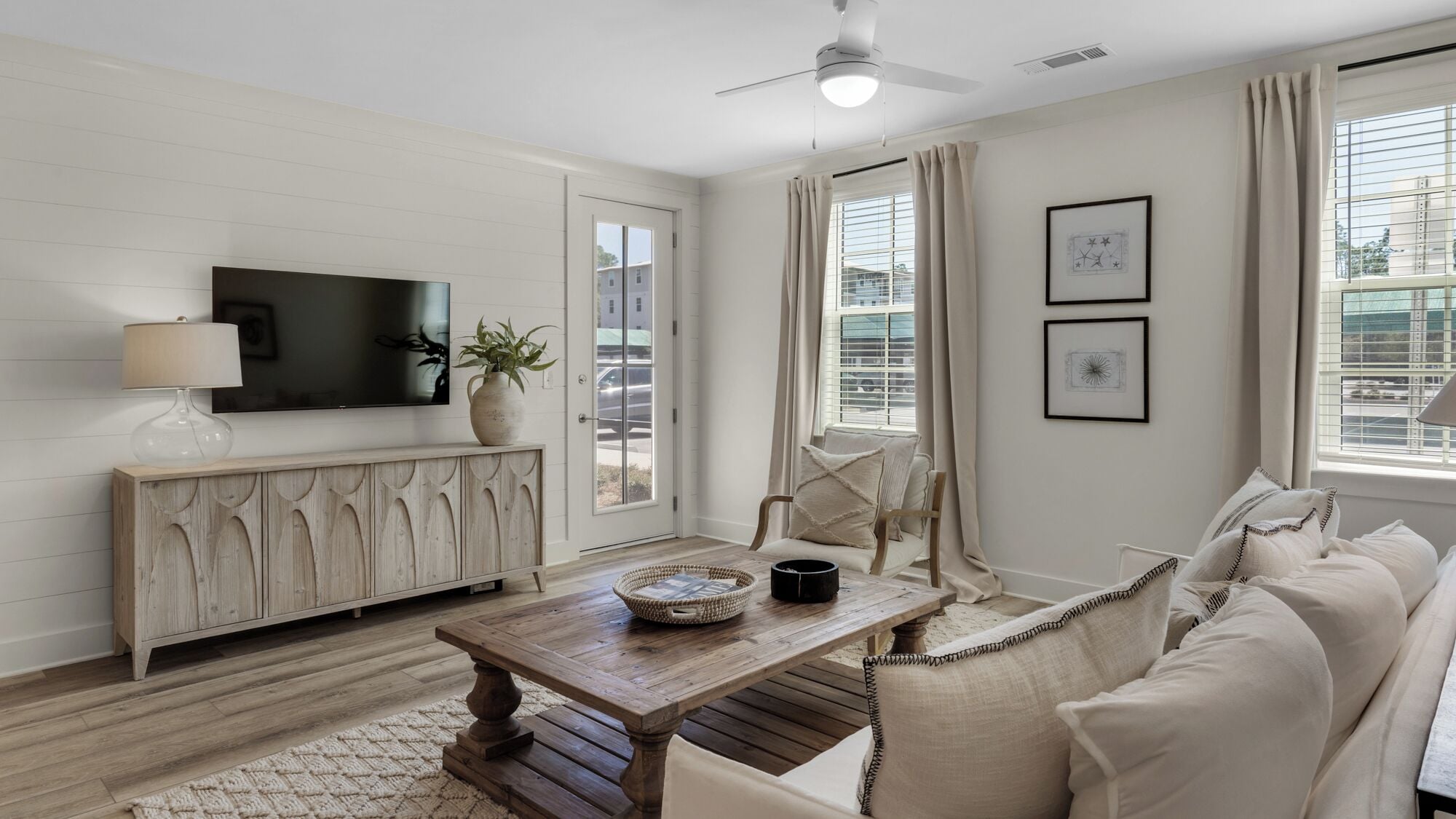A living room with a TV, wooden cabinet, sofa, coffee table, and a ceiling fan.
