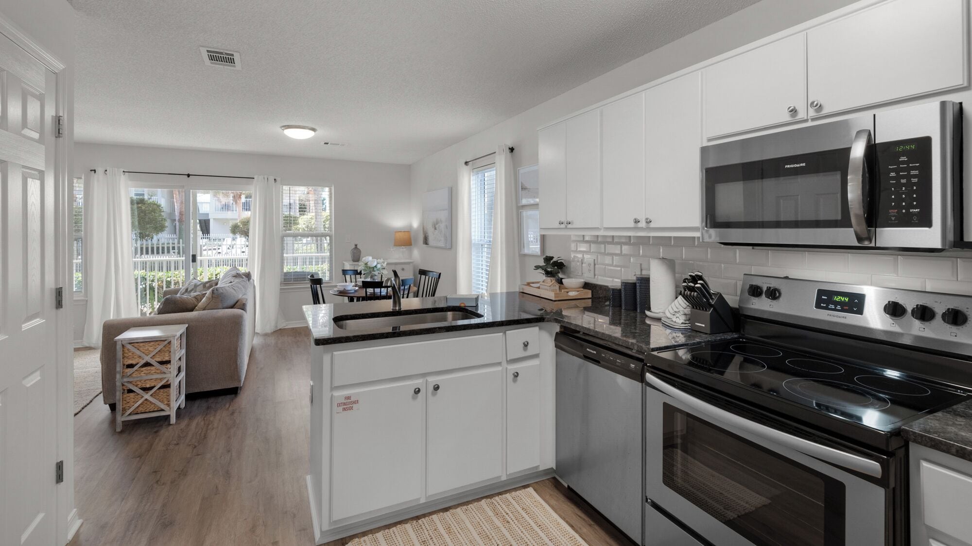 A modern kitchen with white cabinetry, a built-in stove, and a microwave.
