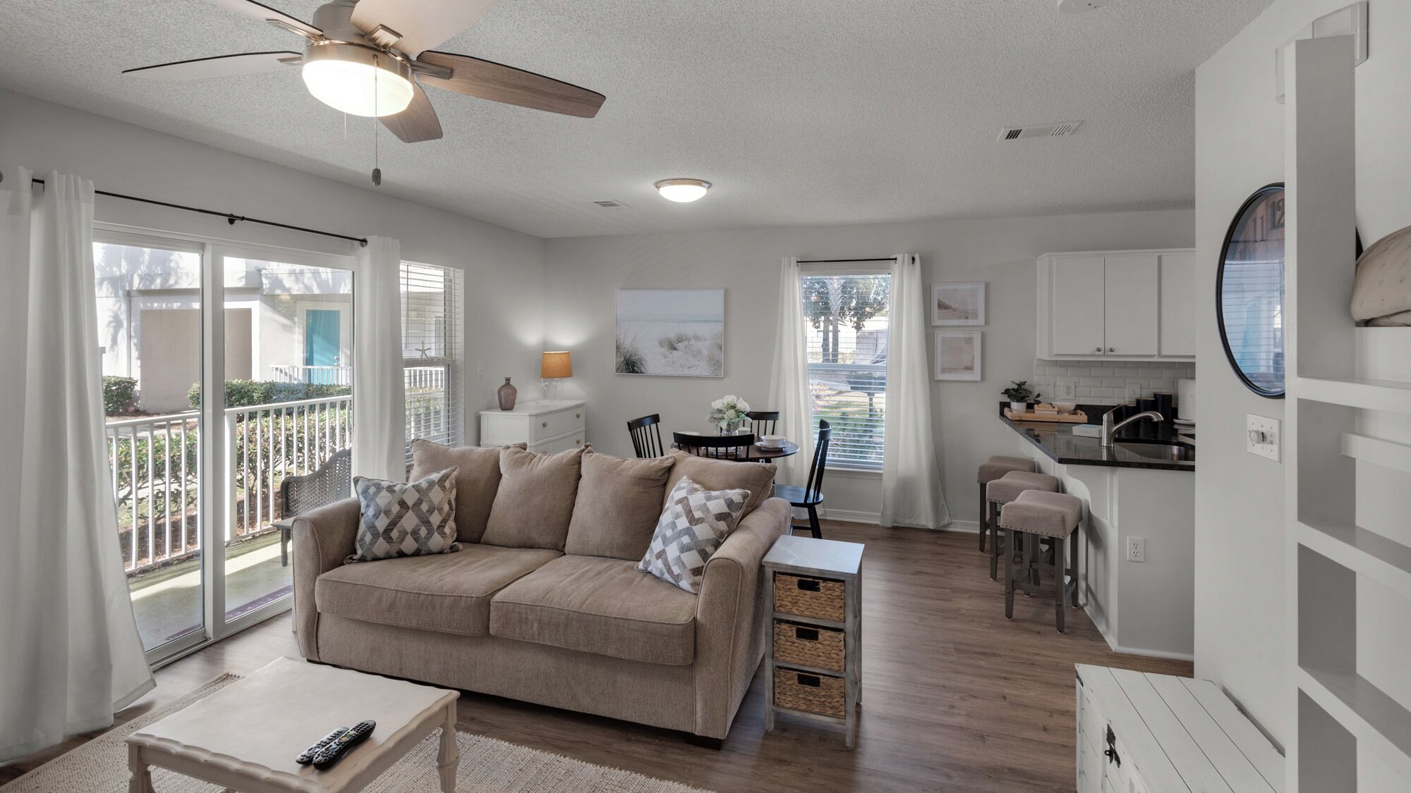 A spacious living room with a beige sofa, a coffee table, and a ceiling fan.