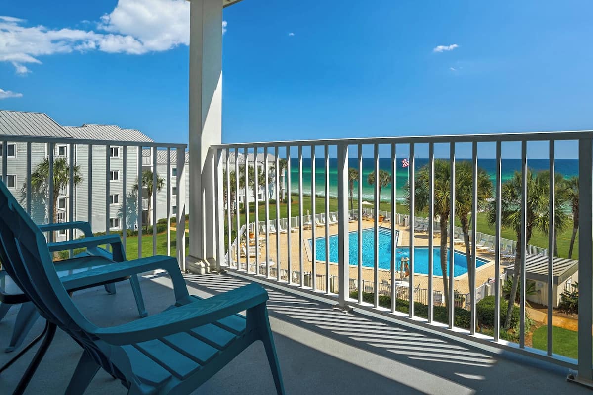 A balcony with a pool, chairs, and a view of the ocean.