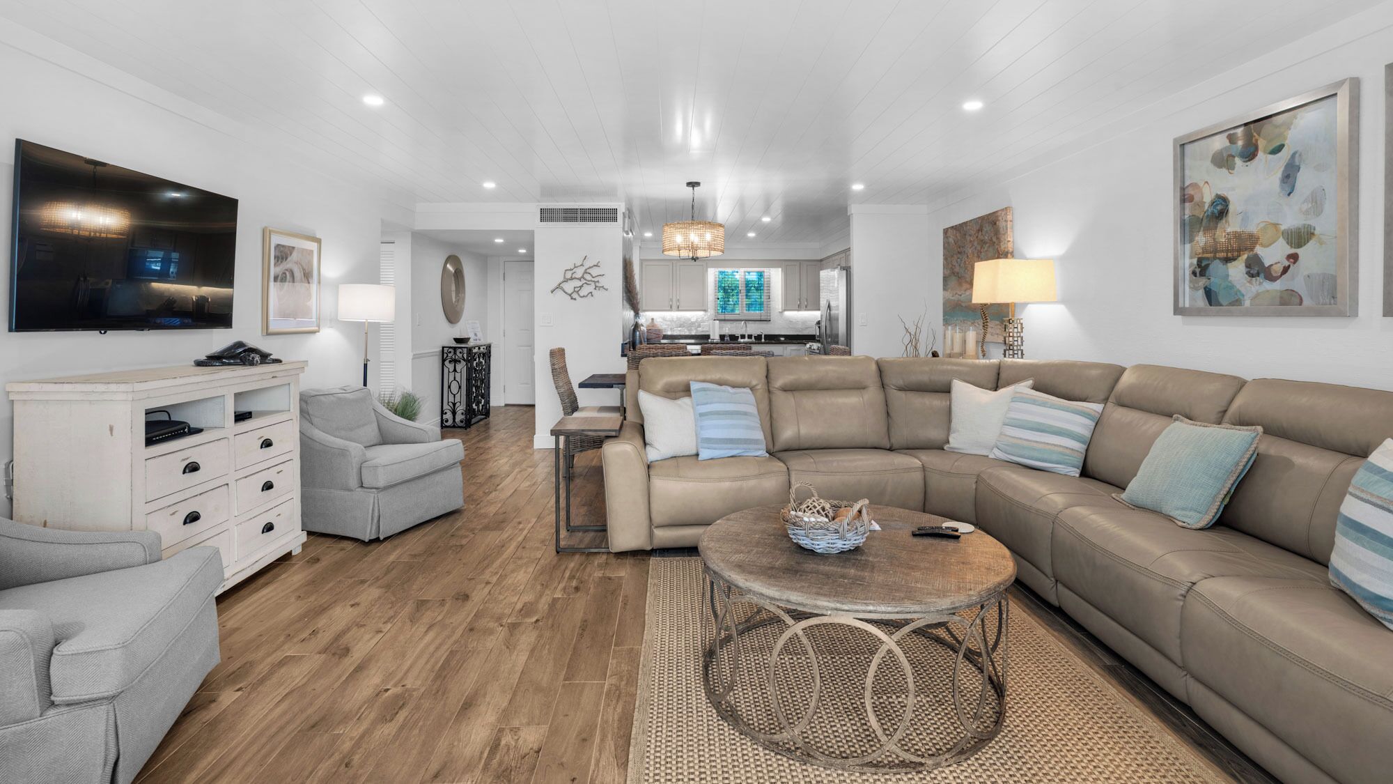 A modern living room with a sectional sofa, a TV, and a dining area.