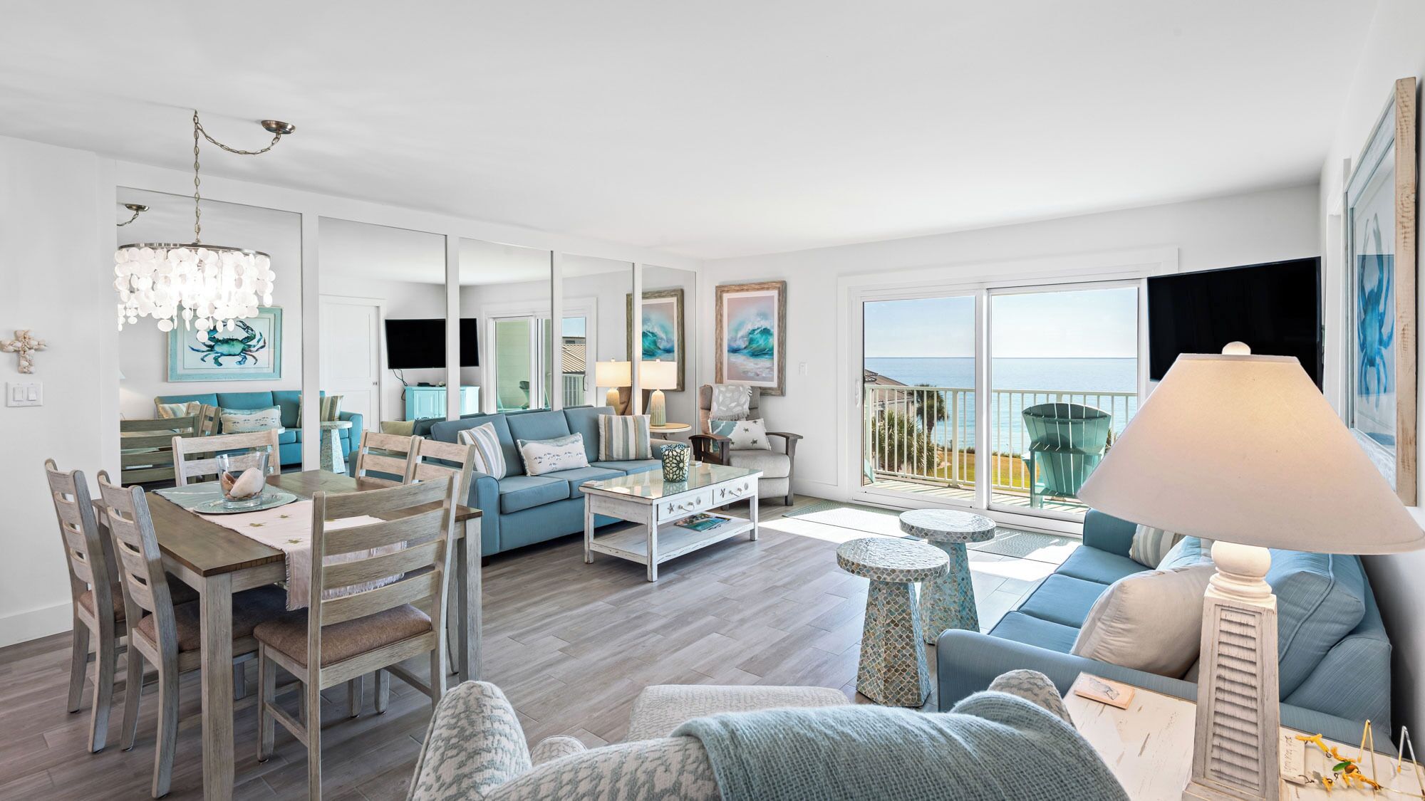 Amplia sala de estar con comedor, un balcón con vista al mar y un ventanal grande.