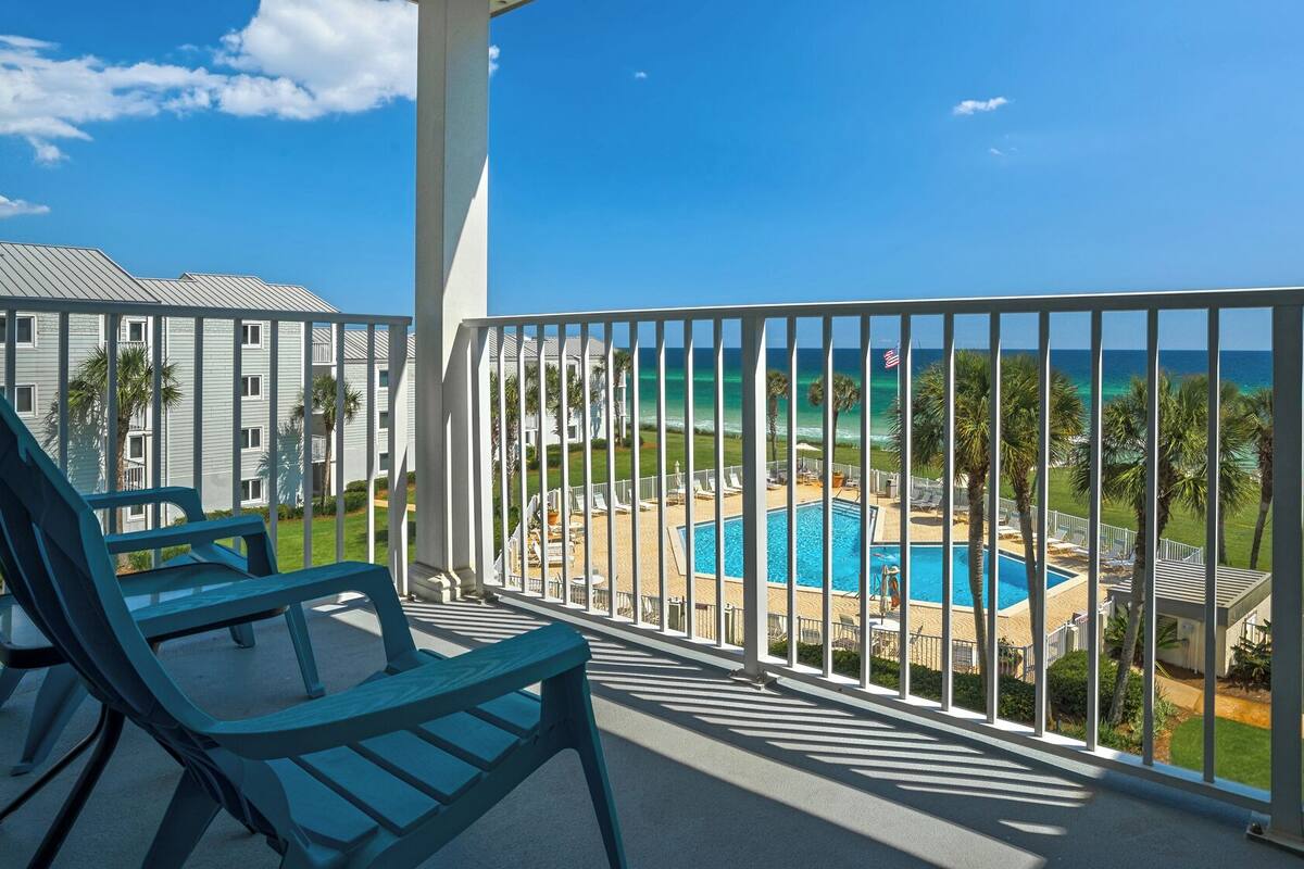 A balcony with a pool, chairs, and a view of the ocean.