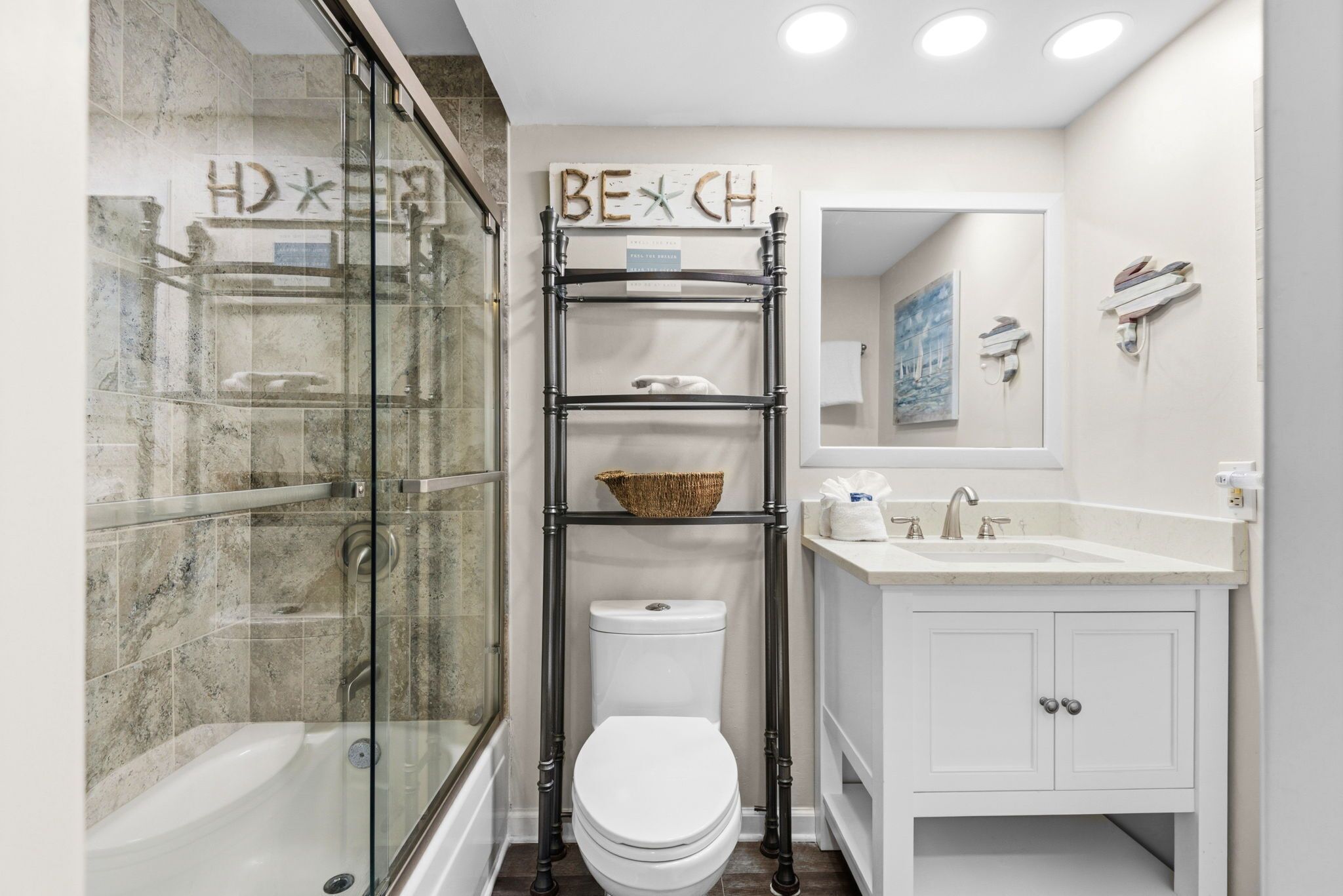 Ein Badezimmer mit Duschkabine, Toilette in Weiß, Waschbecken mit Spiegel und Ablagefläche mit Korb.