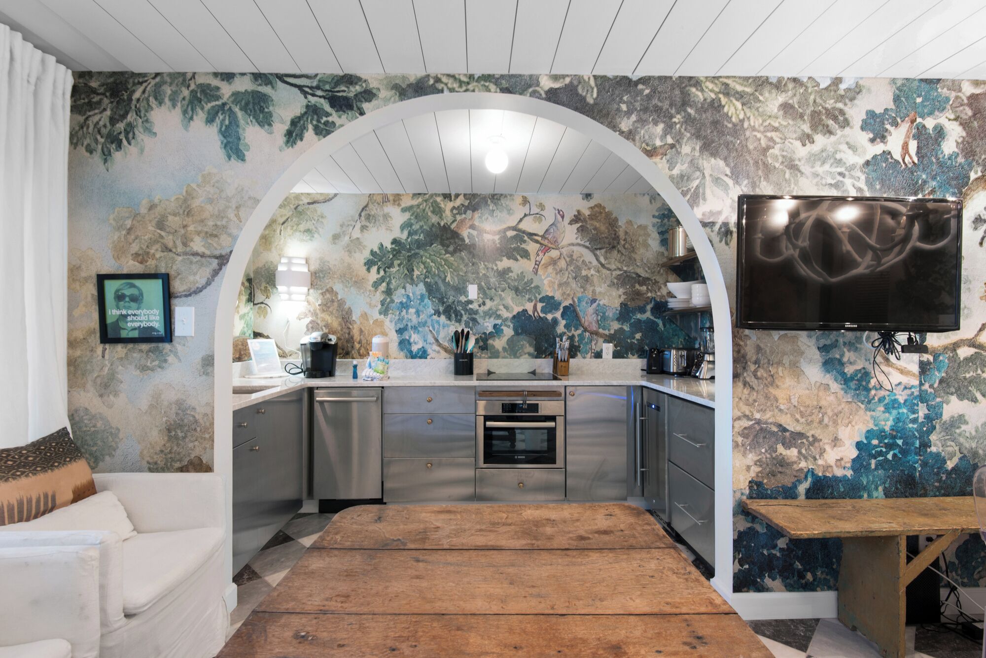 Eine moderne Küche mit Steinrückwand, Edelstahlgeräten und einem Holztisch.