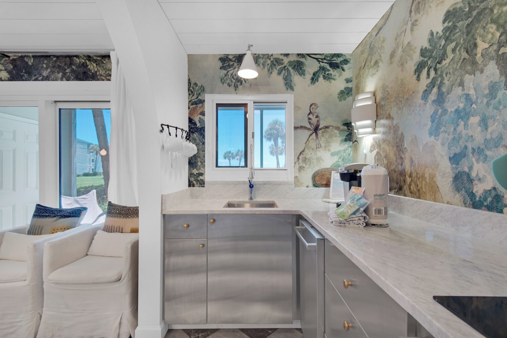 A modern kitchen with a large island, stainless steel appliances, and a view of the outdoors.