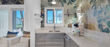 A modern kitchen with a large island, stainless steel appliances, and a view of the outdoors.