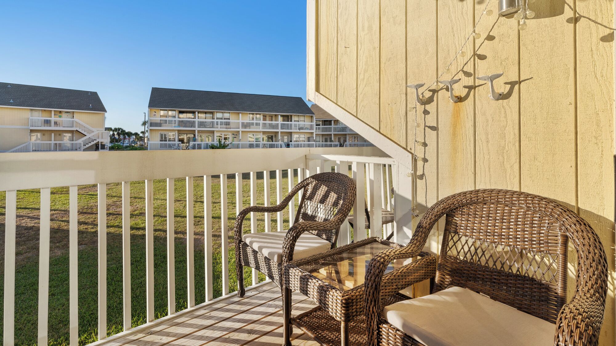 A balcony with wicker furniture and a view of a multi-story building.
