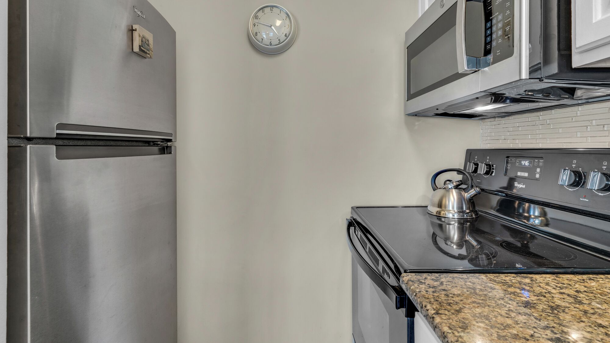 A kitchen with stainless steel appliances, including a refrigerator, microwave, and stove.
