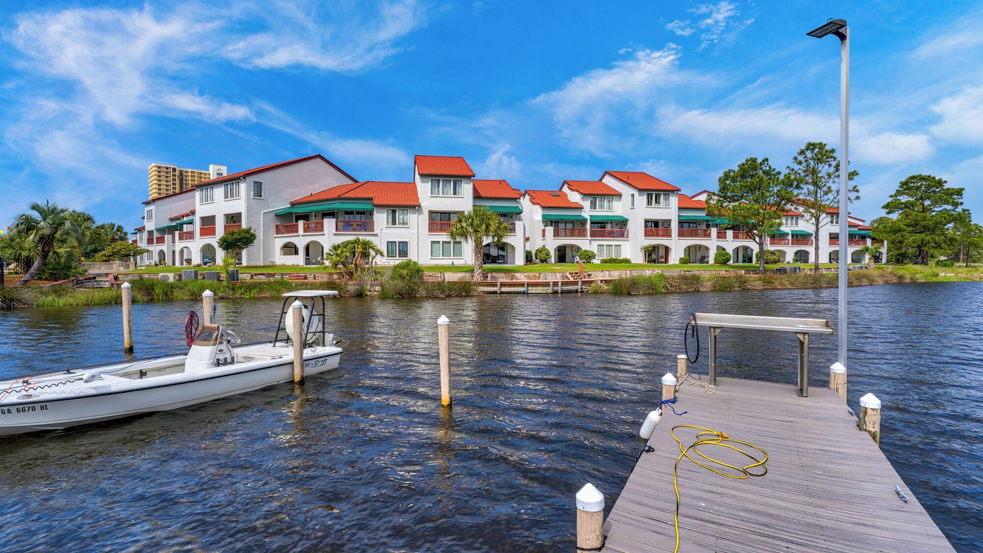 A waterfront hotel with a dock, a boat, and a well-maintained lawn.