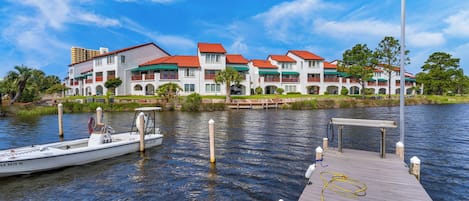 A waterfront hotel with a dock, a boat, and a well-maintained lawn.