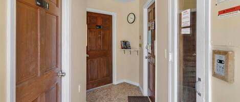 A hallway with wooden doors labeled "Men" and "Women," a clock on the wall, and a sign indicating the sauna is open.