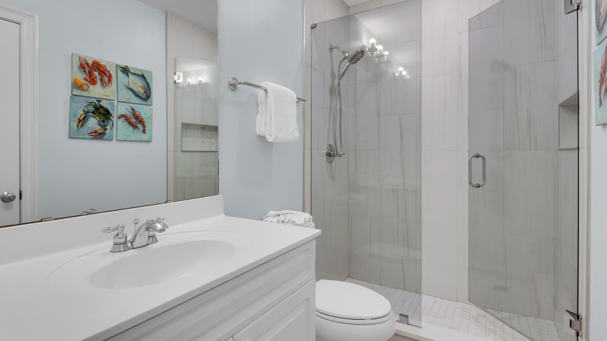 A modern bathroom with a white sink, a toilet, and a glass-enclosed shower.