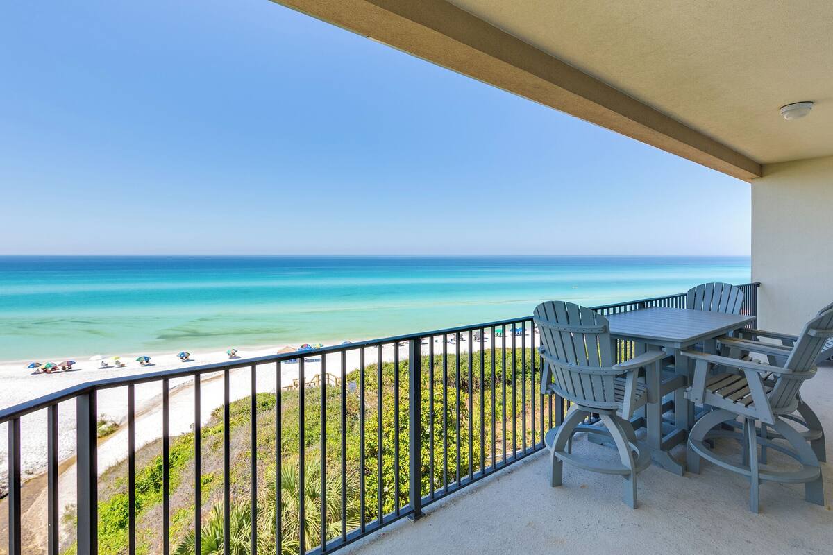 A balcony with a view of the beach and ocean.
