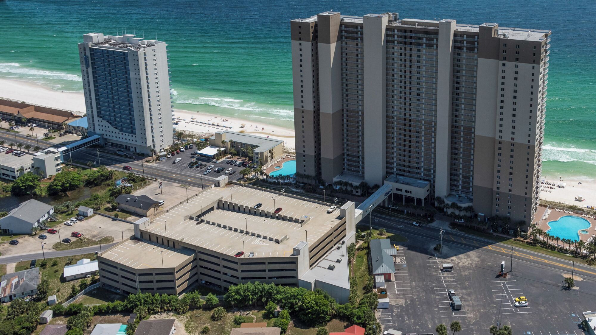 A high-rise hotel with multiple floors, a parking garage, and a beach view.