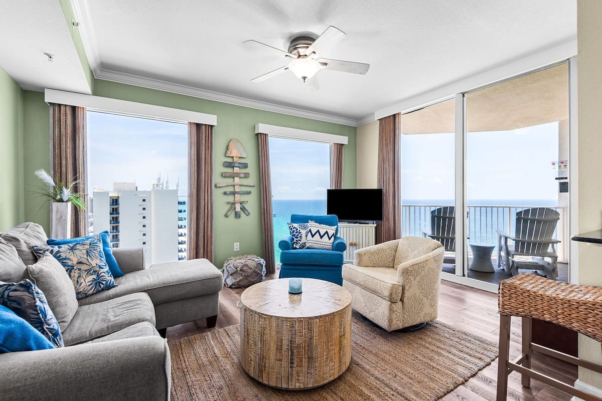 A living room with a sofa, armchair, round coffee table, and a TV.