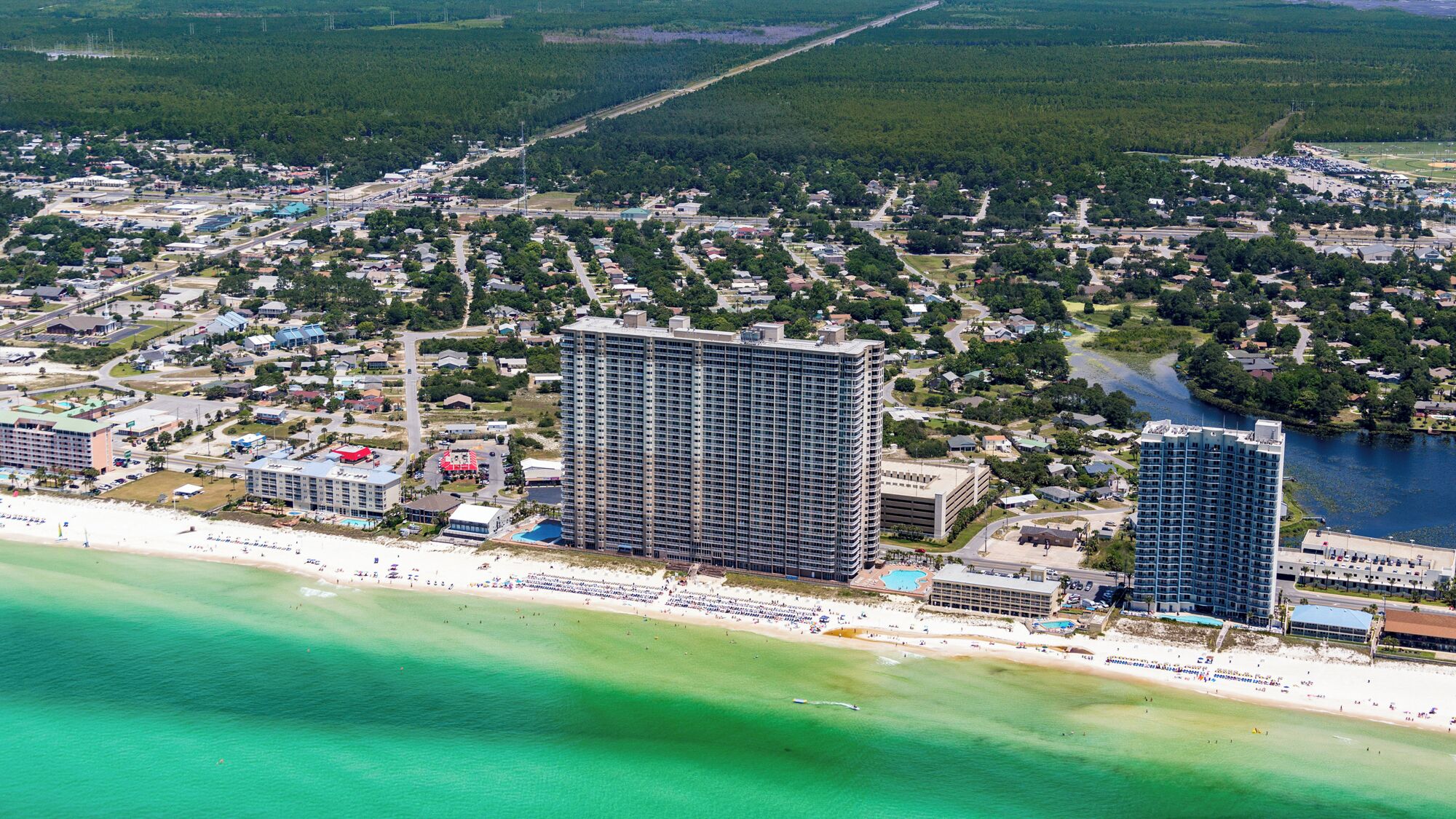 A coastal cityscape with high-rise buildings, a beach, and a river.