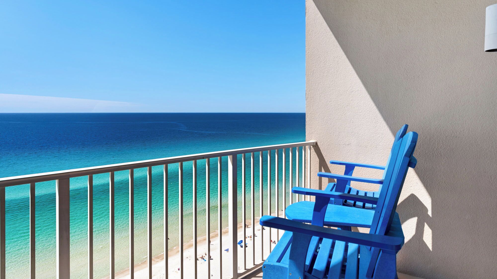 Een balkon met uitzicht op de oceaan, een blauwe stoel en een witte reling.