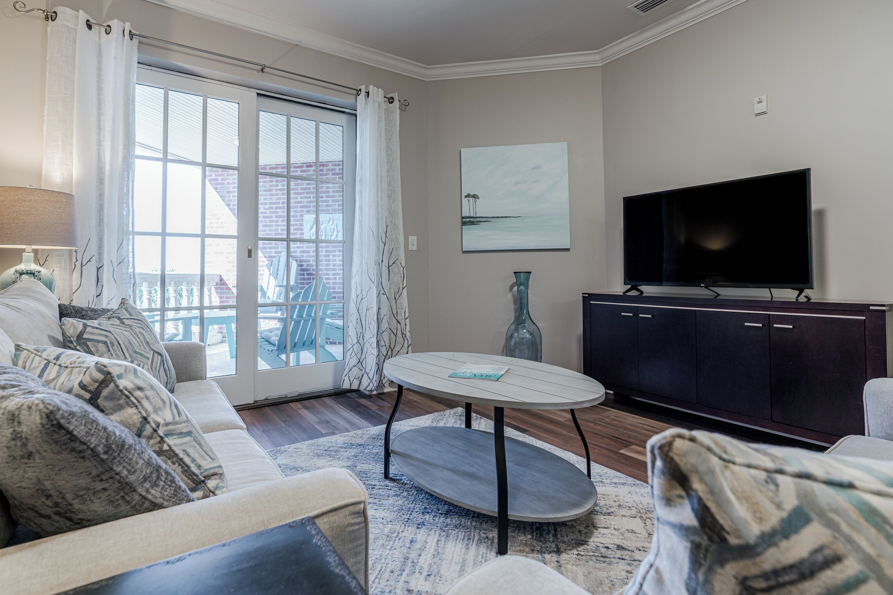 A living room with a sofa, a coffee table, a TV, and a view of the outside.