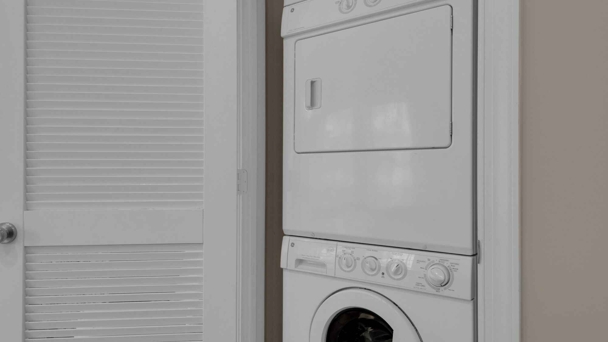 A front view of a stacked washer and dryer unit with a door and a window.