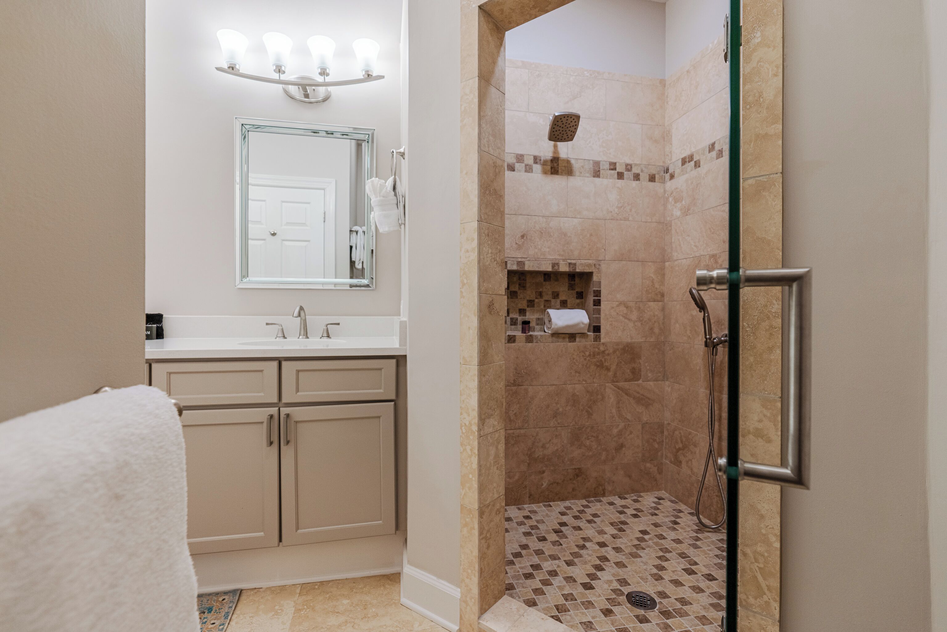 A bathroom with a shower, a sink, and a mirror.