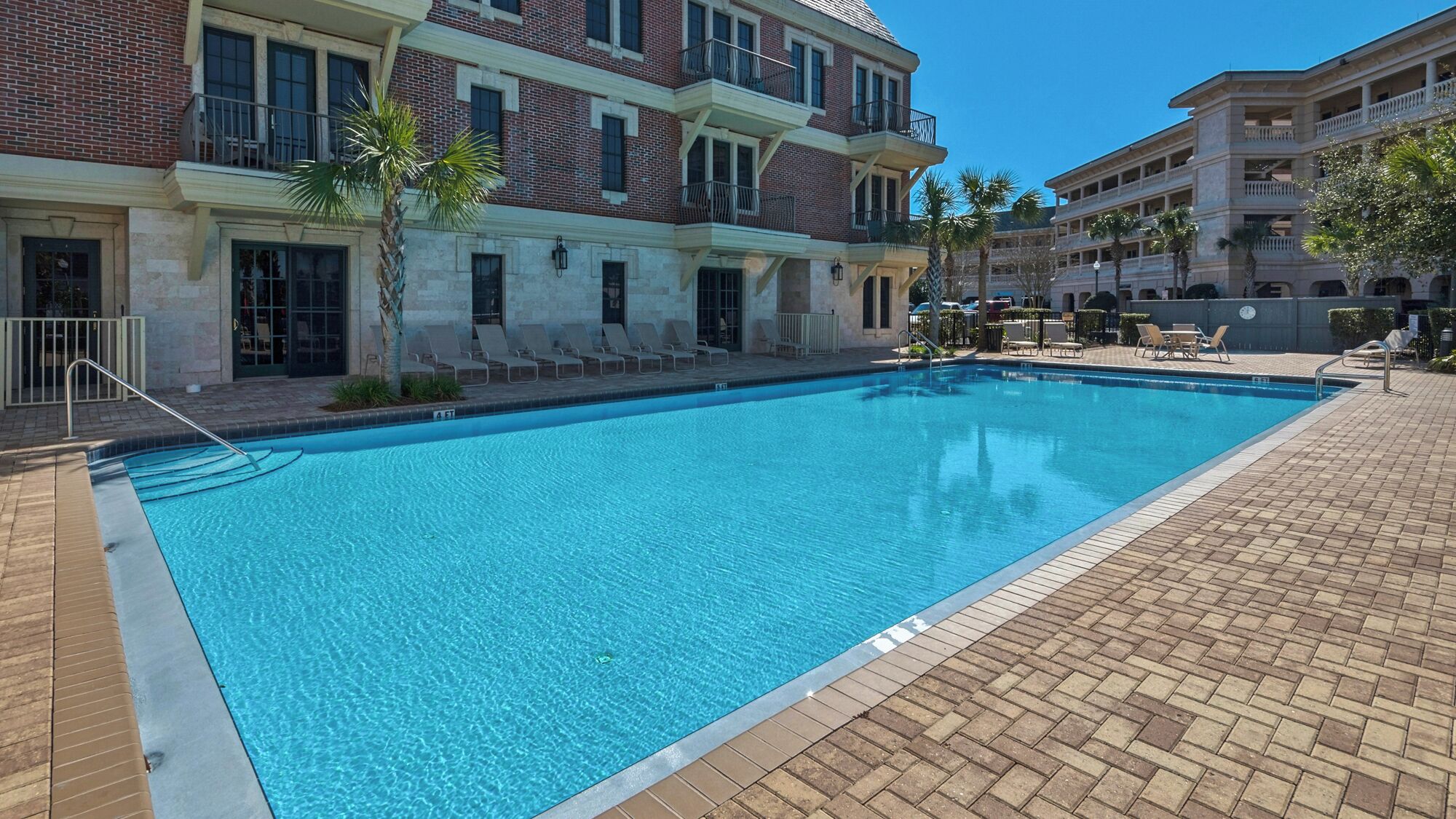 A rectangular swimming pool with a tiled deck surrounding it.