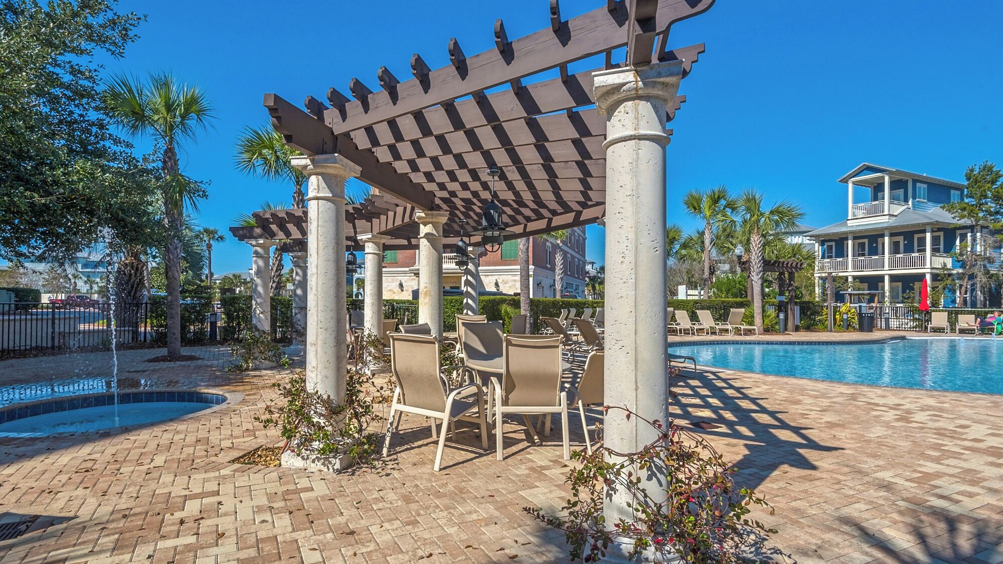 A poolside area with a pergola, lounge chairs, and a pool.