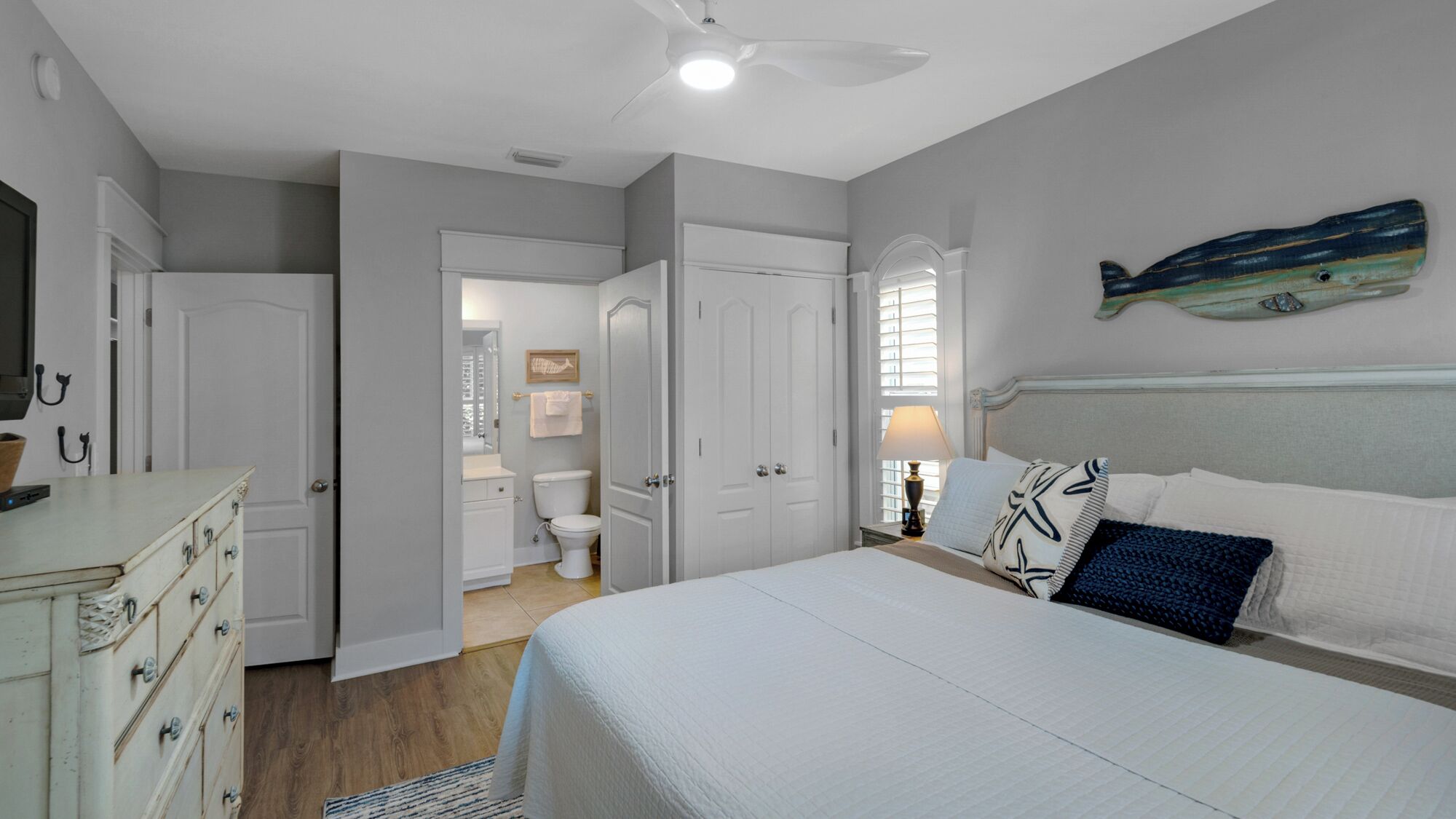 Un dormitorio con cama, cómoda y baño a la vista a través de una puerta abierta.