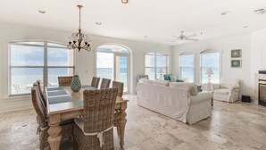 A spacious living area with a dining table, wicker chairs, a sofa, and a fireplace.