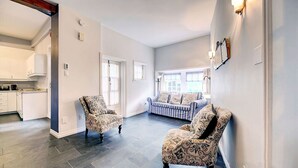 Amplia sala de estar con sillones estampados, un sofá y una cocina al fondo.