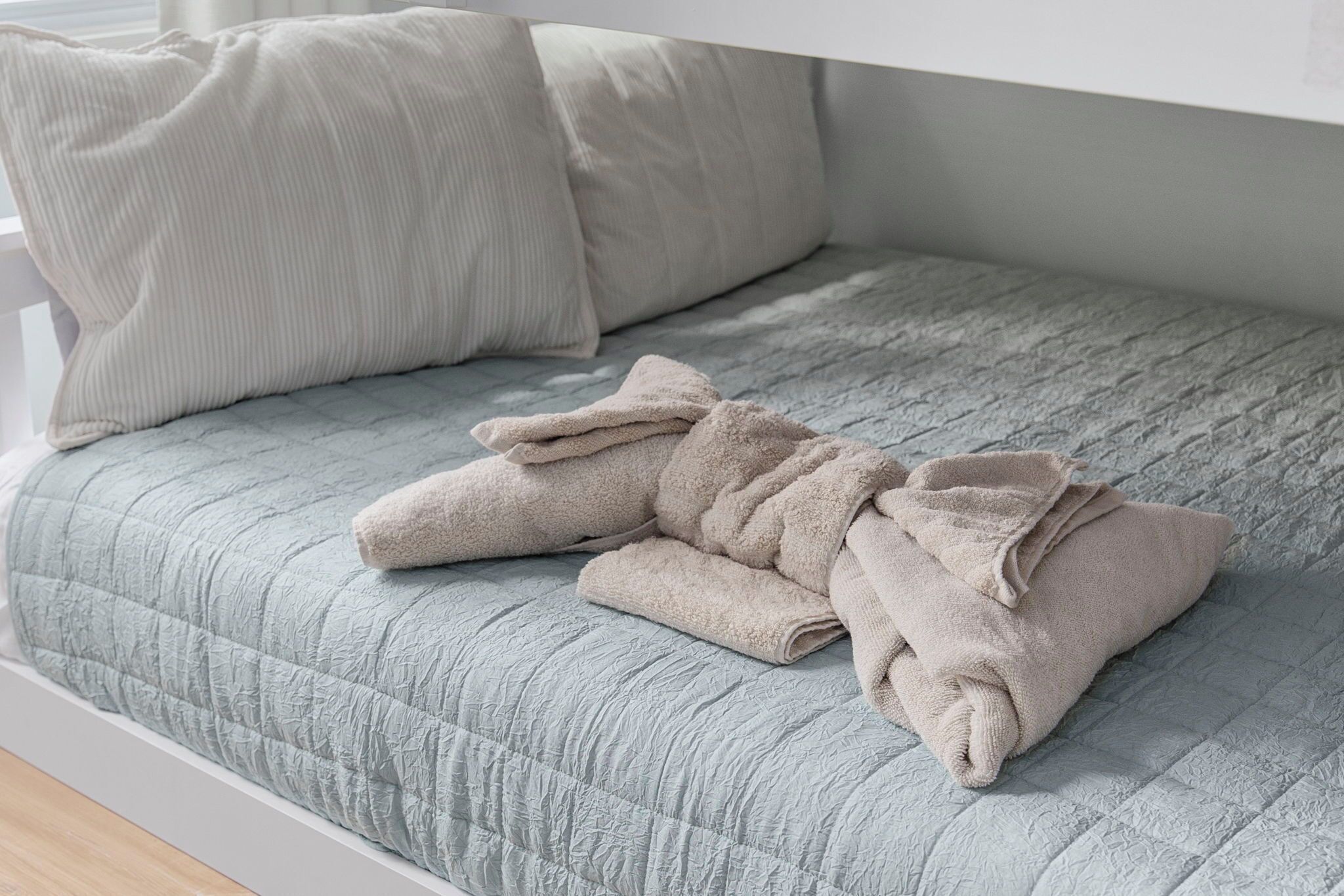 Un letto con una coperta trapuntata grigia e due cuscini color beige.