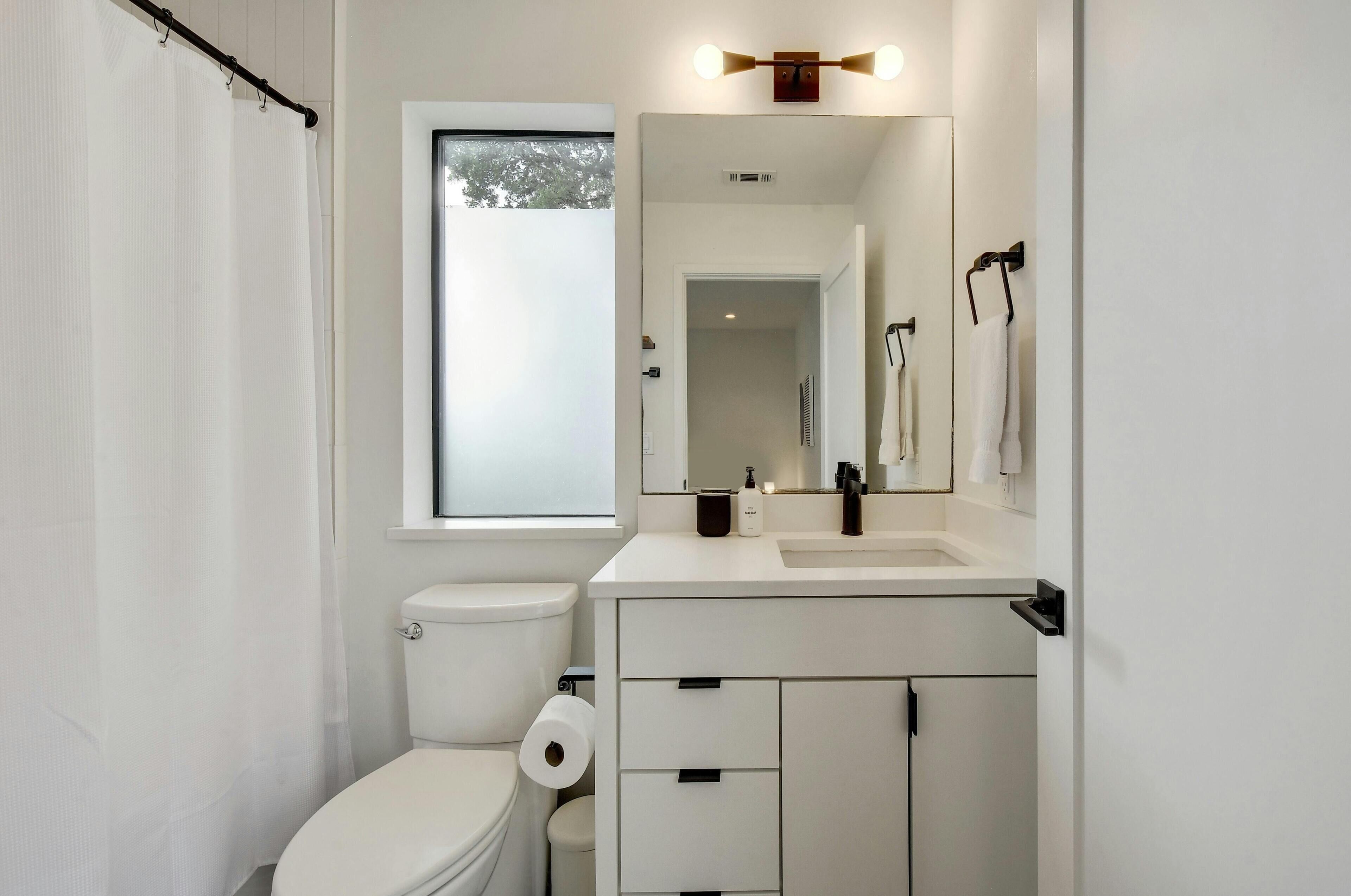 A modern bathroom with a toilet, sink, and mirror.