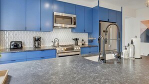 Eine moderne Küche mit blauen Schränken, einer Edelstahl-Mikrowelle, einem Gasherd und einem Spülbecken.