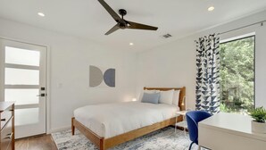 Ein Schlafzimmer mit Bett, Schreibtisch, Stuhl und Deckenventilator.