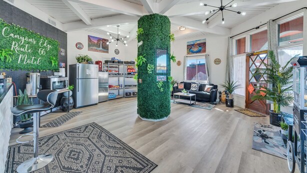 A modern motel interior with a central green wall, kitchen area, seating, and a large window. - Canyons Edge Route 66 Motel (Ash Fork)